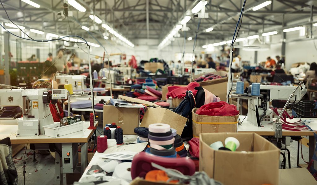 Lini produksi pabrik sepatu custom di Indonesia dengan mesin jahit dan bahan upper.